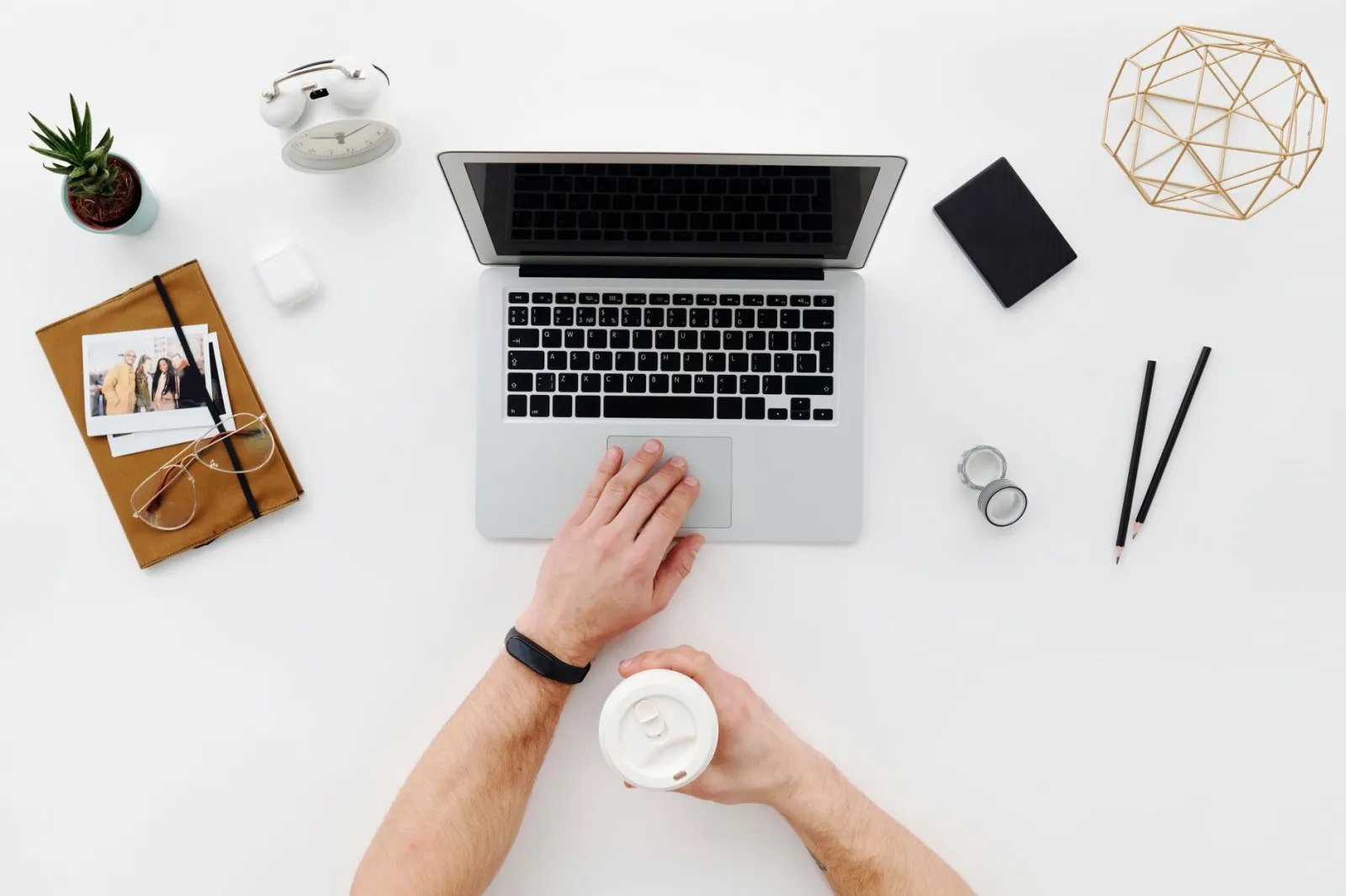 A top view of a minimalist desk featuring a laptop, coffee cup, and office supplies.