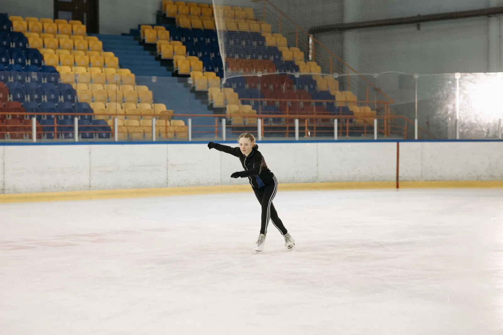A young woman elegantly figure skating on an indoor ice rink, showcasing her skills.