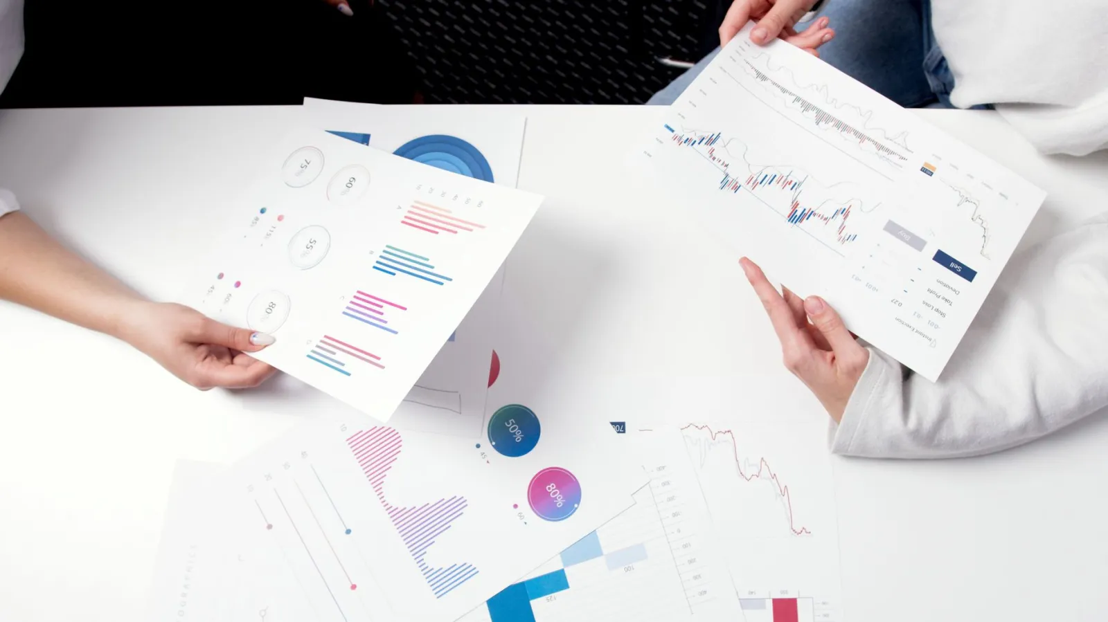 Hands holding business charts and graphs during a meeting, showcasing financial analysis and investment strategy.