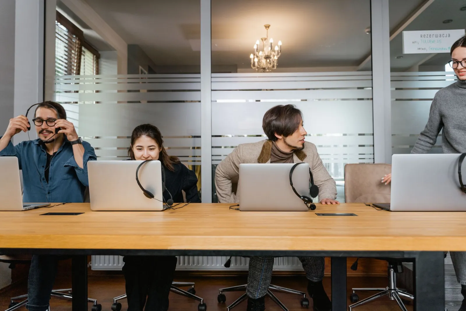 Business professionals working in an office with laptops and headsets, engaging in teamwork.