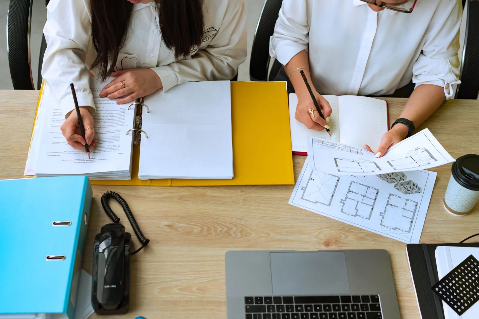 Two colleagues collaborating on architectural designs, reviewing plans and documents at a desk.
