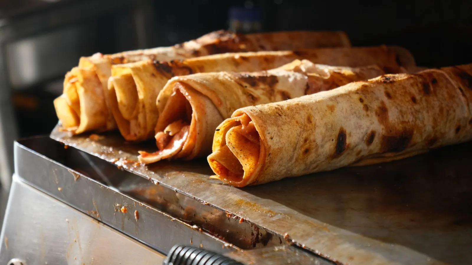 Close-up of traditional Turkish Dürüm wraps being grilled, showcasing delicious street food.